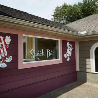 A colorful exterior of a snack bar featuring playful cartoon character murals.