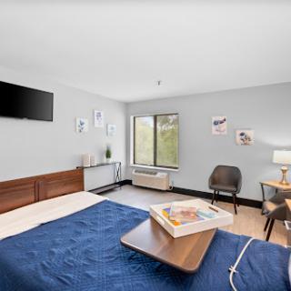 A cozy and modern hotel room featuring a comfortable bed, a television, and stylish decor.