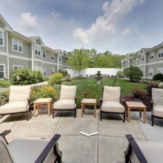 A well-maintained courtyard with comfortable outdoor seating and a central fountain, surrounded by an apartment complex.