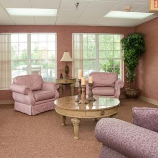 A cozy living room with pink armchairs, a round coffee table, and large windows allowing natural light to fill the space.