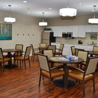 A spacious dining area with multiple tables, comfortable seating, and a kitchen space in the background.