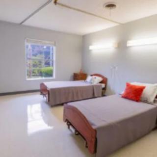 A minimalist bedroom with two single beds and a window letting in natural light.