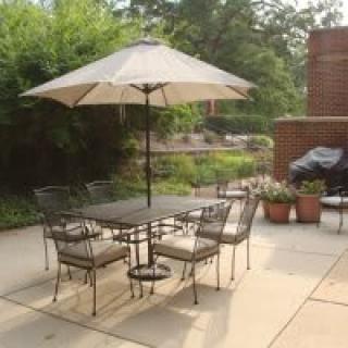 A patio with a table, chairs, and an umbrella set up in a garden area.