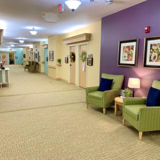 A well-lit hallway with comfortable seating and colorful artwork adorns the walls.