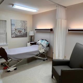 A hospital room with a bed, curtain, and seating area.