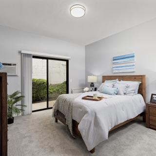 A modern and cozy bedroom with a large bed, stylish decor, and natural light from sliding glass doors.