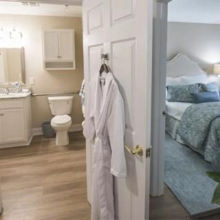 A cozy bedroom and bathroom setup with a bathrobe hanging on the door.