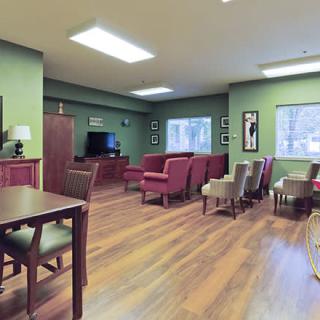 A cozy room with green walls, featuring a seating area with red chairs and a television.