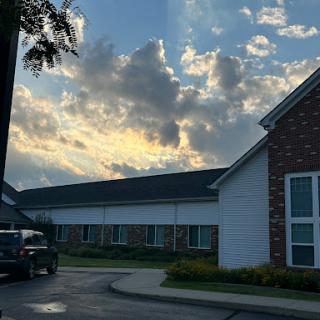 A serene view of a residential building under a cloudy sky at sunset.