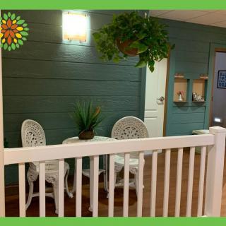 A cozy outdoor patio setting with white chairs and a table, surrounded by plants.