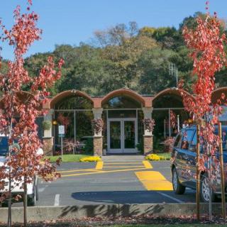 An entrance to a building surrounded by autumn trees and parked vehicles.