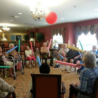 A group of elderly individuals participating in a fun indoor activity with balloons.
