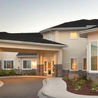 A modern residential building with a driveway and landscaped surroundings.