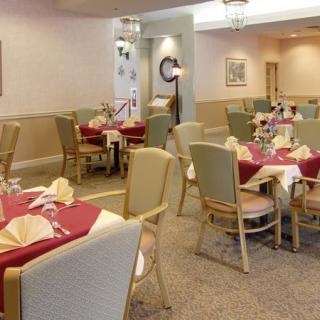 An elegantly set dining room with multiple tables and chairs prepared for service.