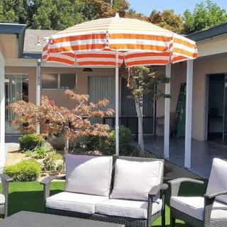 A cozy outdoor patio setup with a striped umbrella and cushioned seating.