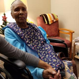 An elderly woman in a wheelchair being comforted by another person.
