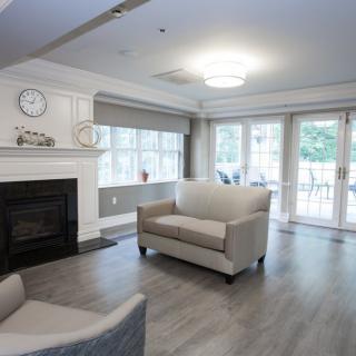A modern living room with a fireplace and large windows, featuring comfortable sofas and a hardwood floor.