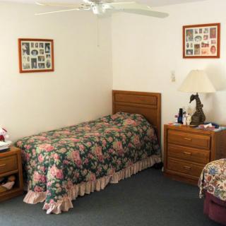 A cozy bedroom featuring twin beds with floral bedding, wooden nightstands, and a ceiling fan.