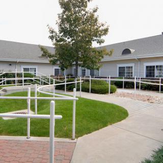 A beautifully designed accessible walkway surrounded by greenery leading to a residential building.