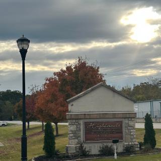 A scenic view featuring a sign amidst autumn foliage under a cloudy sky.