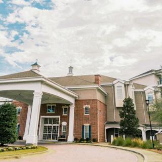 A grand building with a prominent entrance and columns under a cloudy sky.
