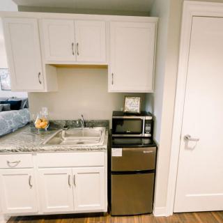 A compact kitchen area with white cabinets, a sink, a microwave, and a mini fridge.