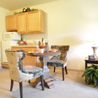 A cozy dining area with a round table and comfortable chairs adjacent to a small kitchen.