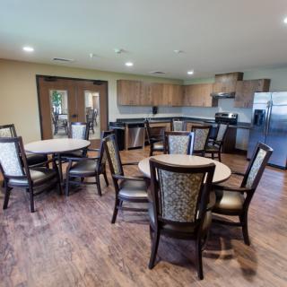 A modern kitchen and dining area with round tables and chairs, featuring an open layout.
