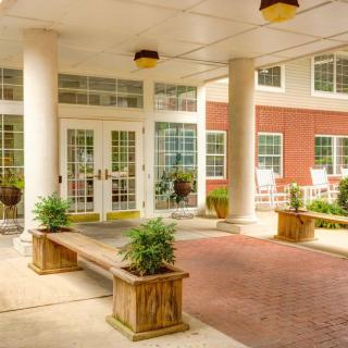 An inviting entrance with columns and benches, featuring plants for a welcoming ambiance.
