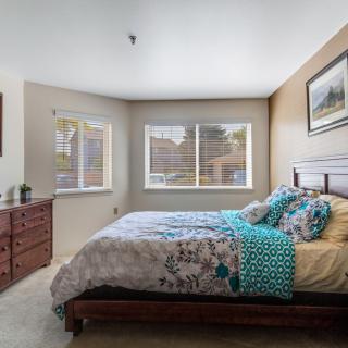 A cozy bedroom with a large bed, floral bedding, and bright natural lighting.