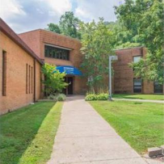 A welcoming entrance to a brick school building surrounded by lush greenery.
