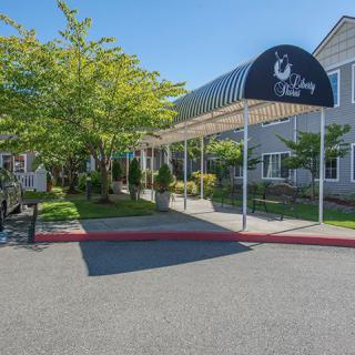 The exterior view of a building entrance with an awning and surrounding greenery during the daytime.