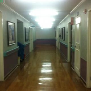 An empty corridor in a hospital with polished floors and bright lighting.
