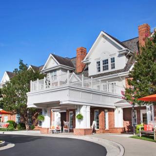 A charming residential building with a large balcony and surrounded by trees on a clear day.