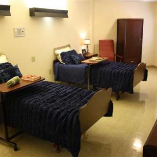 A hospital room with two beds and basic furnishings.