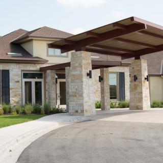 A modern house with stone exterior and a covered driveway.