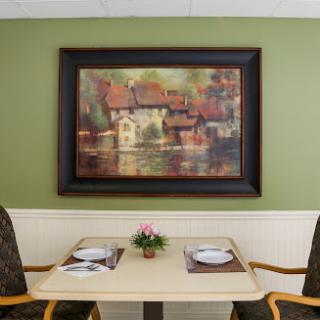 A cozy dining area featuring a beautiful painting and a neatly set table.