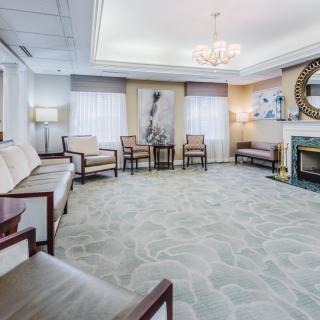 A spacious and elegantly decorated living room featuring a fireplace, modern furniture, and a chandelier.