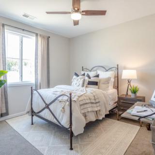 A modern bedroom featuring a neatly made bed, bedside tables with lamps, and a large window letting in natural light.