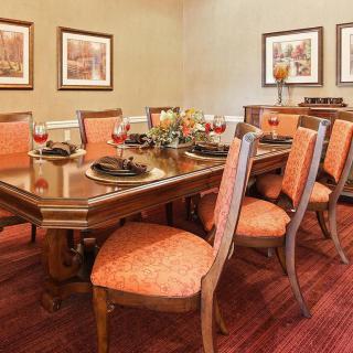 A beautifully arranged dining room with a wooden table and upholstered chairs, adorned with elegant tableware and surrounded by artwork.