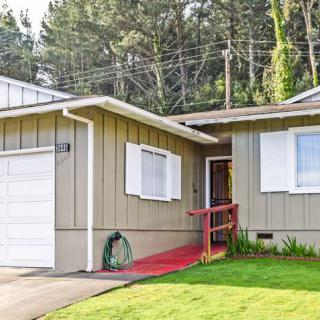 A single-story house with a garage and front yard, surrounded by trees.