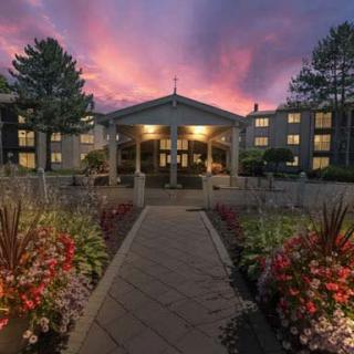 A beautifully lit building at sunset, framed by vibrant gardens and a welcoming pathway.