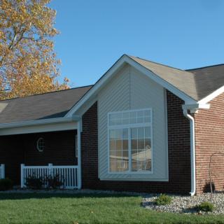 A suburban brick house with a well-kept lawn and clear blue sky.