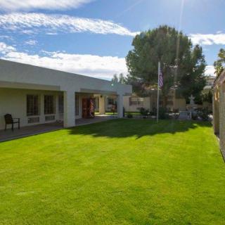 A sunny day view of a building with a well-kept lawn and trees.