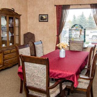 A cozy dining room with a red tablecloth on the table, surrounded by wooden chairs and a china cabinet.