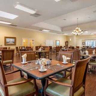 An elegant dining room with neatly arranged tables and chairs under a chandelier.