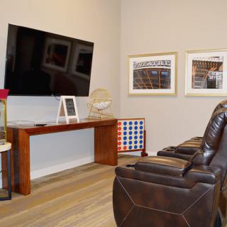 A cozy living room setup with plush reclining chairs facing a mounted television, complemented by tasteful decor.