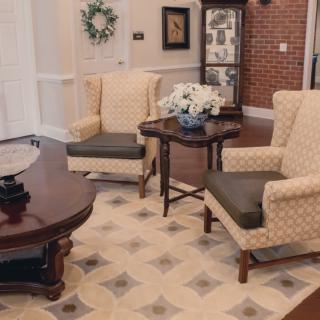 A cozy living room with armchairs and coffee tables, featuring elegant decor and a patterned rug.