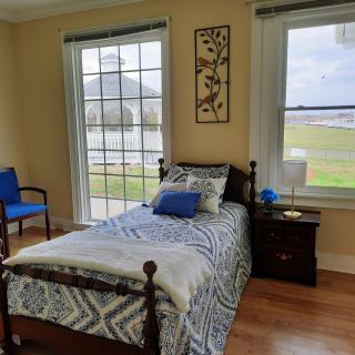 A cozy bedroom with a single bed and large windows overlooking a scenic view.