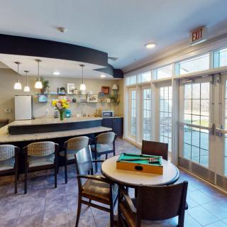 A modern kitchen and dining area with a bar counter, stylish chairs, and large windows letting in natural light.